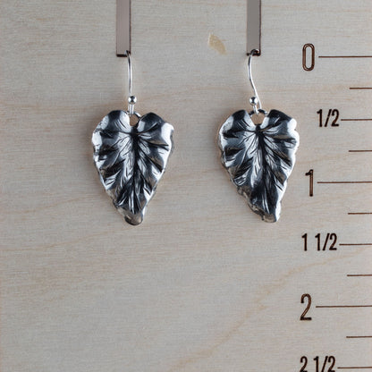 Sterling silver leaf dangle earrings with detailed vein texture and heart-shaped foliage design, displayed on Wood ruler for scale