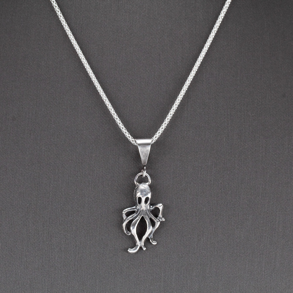 Handcrafted sterling silver octopus pendant with oxidized finish, hanging on a sparkling chain – ocean-inspired artisan necklace by Divella Designs, displayed on gray background.