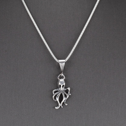 Handcrafted sterling silver octopus pendant with oxidized finish, hanging on a sparkling chain – ocean-inspired artisan necklace by Divella Designs, displayed on gray background.