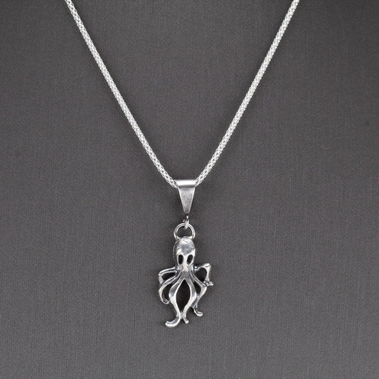 Handcrafted sterling silver octopus pendant with oxidized finish, hanging on a sparkling chain – ocean-inspired artisan necklace by Divella Designs, displayed on gray background.