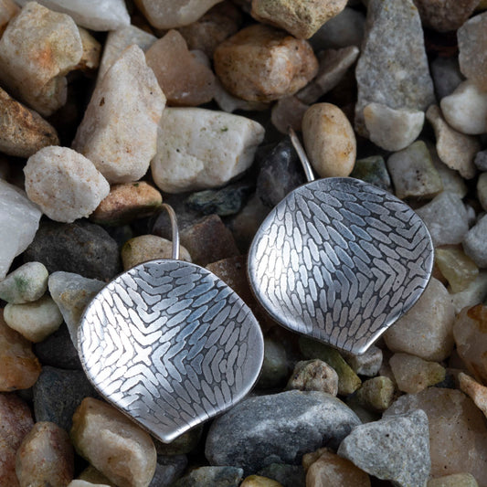 Silver earrings with textured design on a bed of small stones