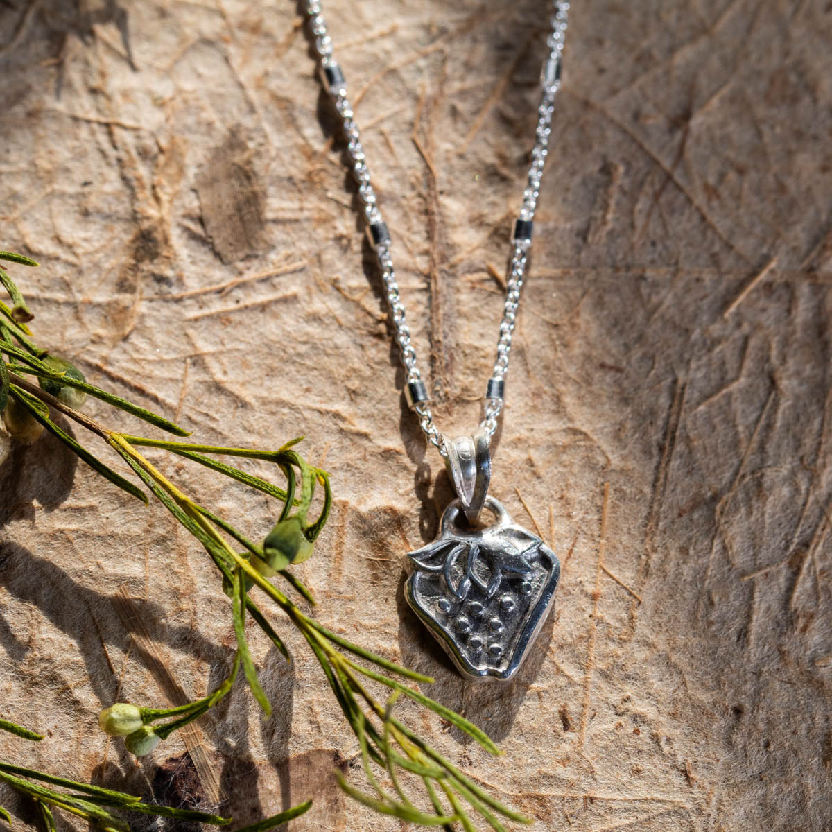 Handmade fine silver strawberry pendant necklace with botanical leaf details, featuring a whimsical nature-inspired design on a delicate silver chain.