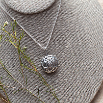 Handcrafted sterling silver pendant necklace featuring a deep red garnet gemstone in a floral shadowbox design, with intricate botanical detailing and oxidized vintage finish