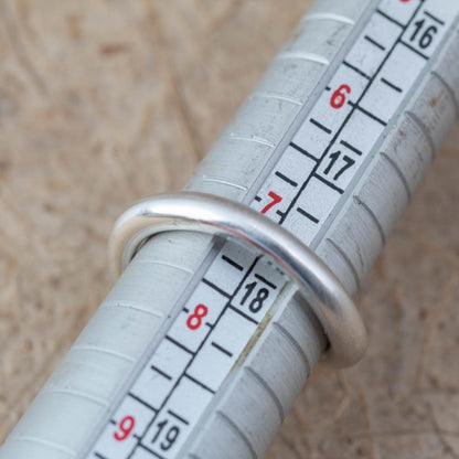 Close-up of a measuring tape with a ring on a wooden surface