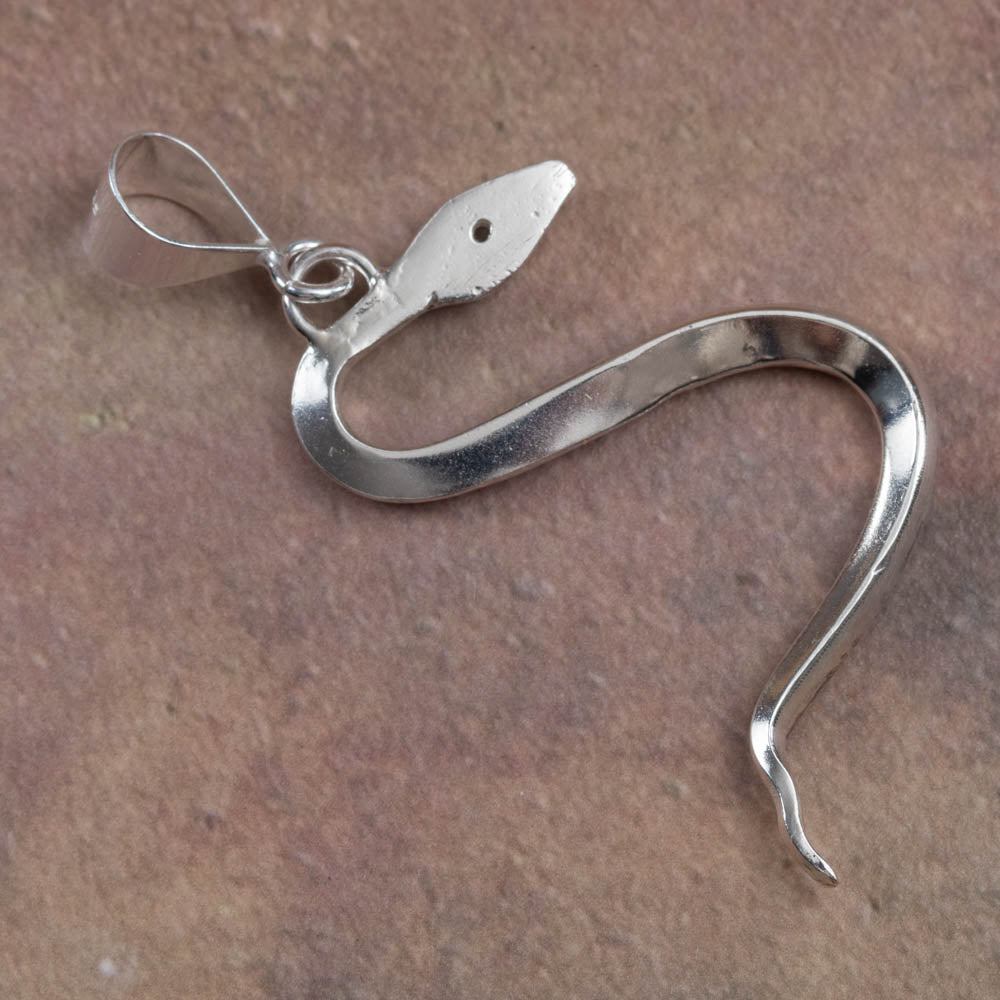 Back of Ssilver hook-shaped pendant on a brown surface