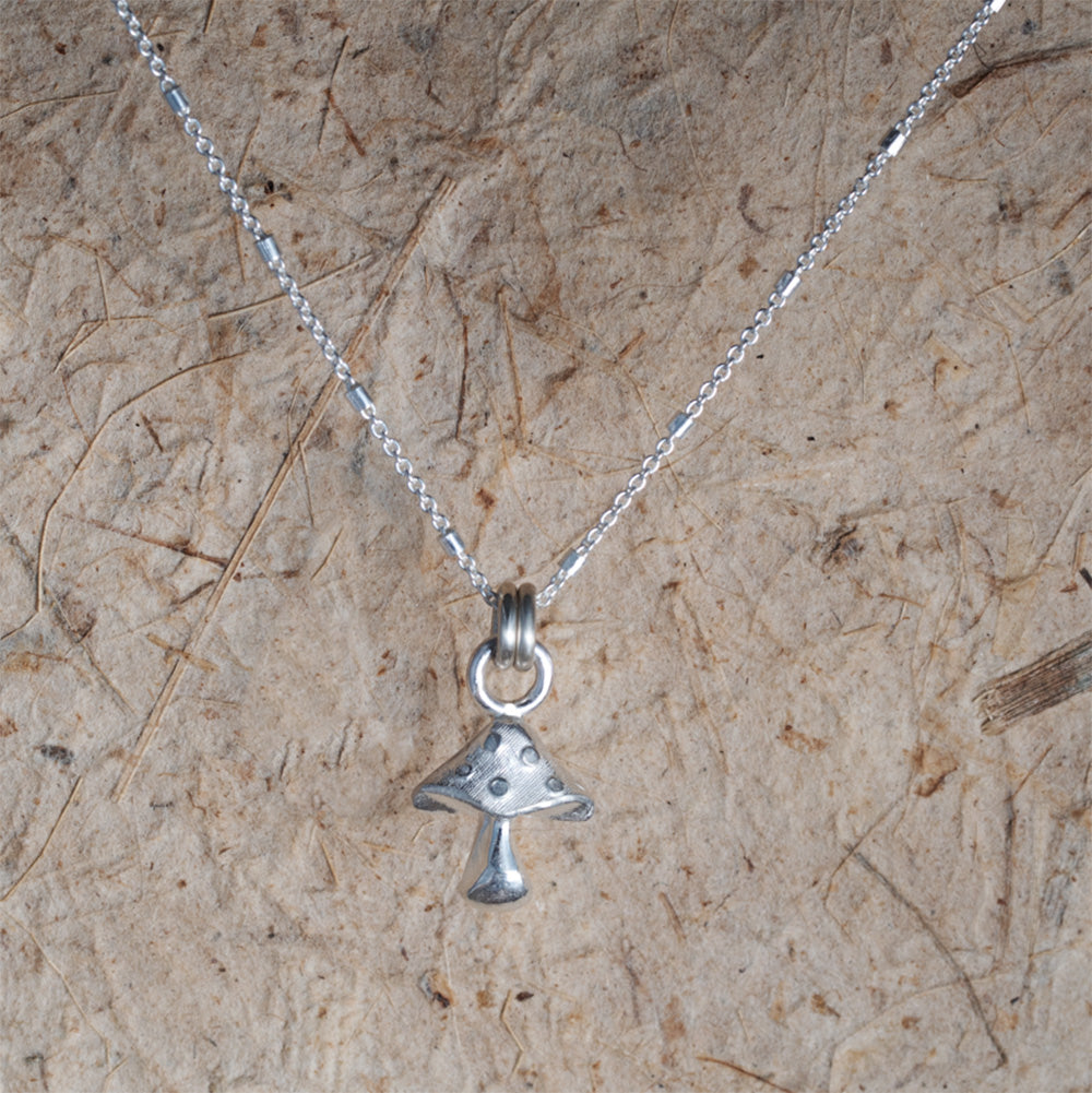 Silver necklace with a pendant hanging on a textured beige surface