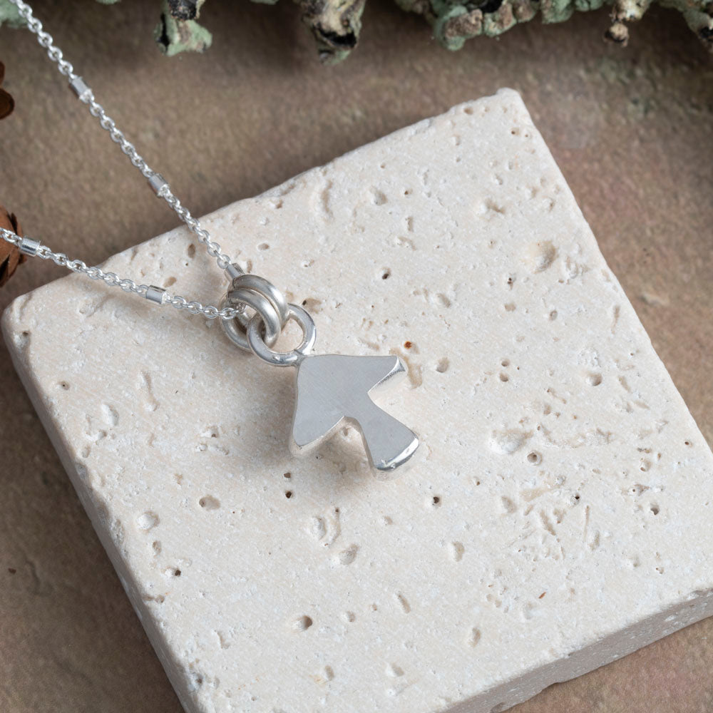 Back of Silver necklace with a unique mushroom pendant on a textured stone surface