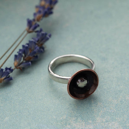 Handmade mixed metal ring in natural light with soft botanical styling