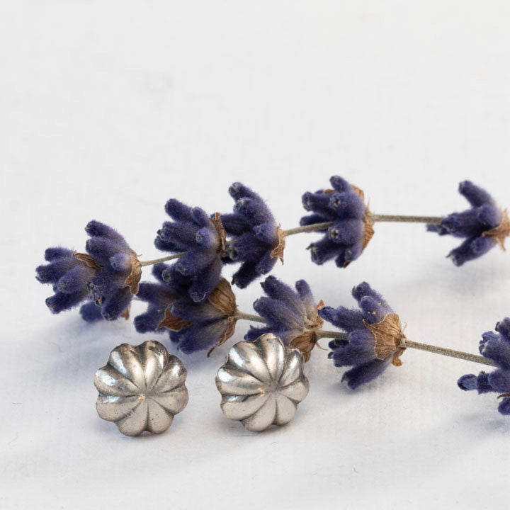 Fluted solid silver stud earrings styled with dried lavender sprigs on a white background.