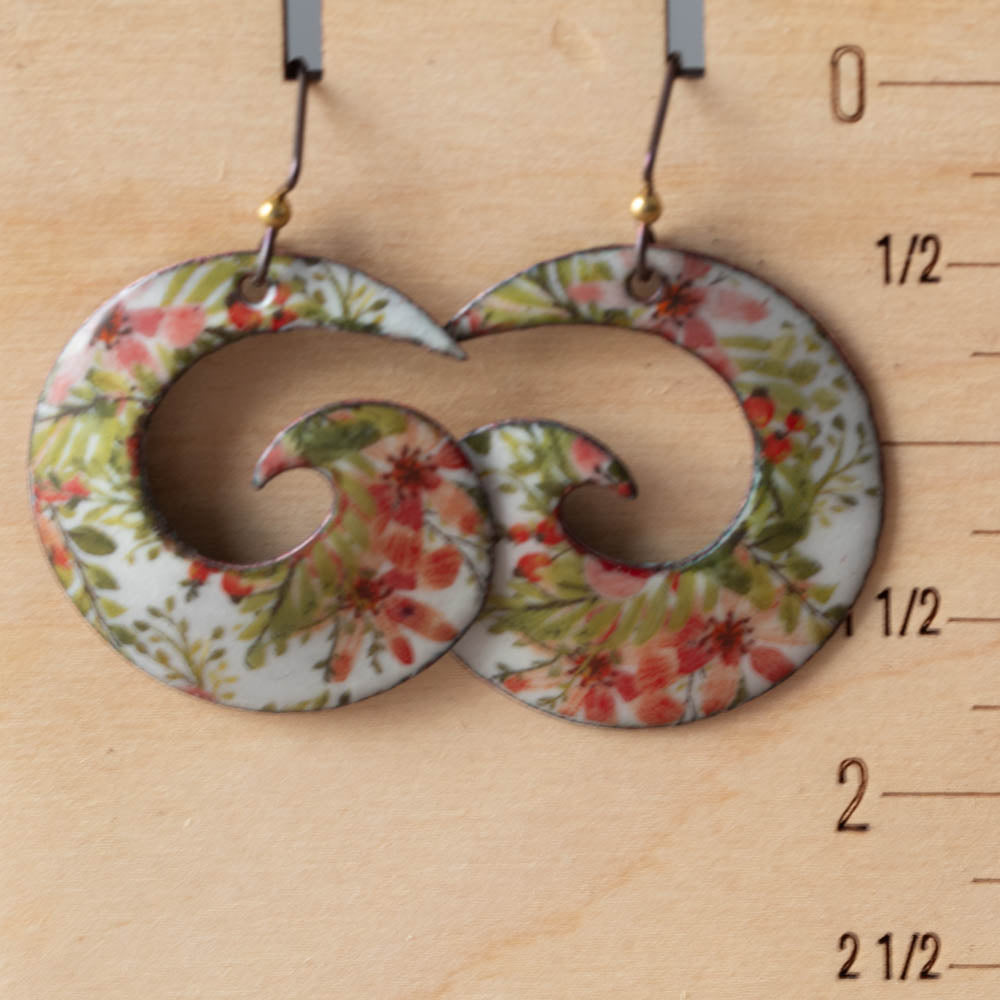 Floral patterned earrings on a wooden surface with measurement scale