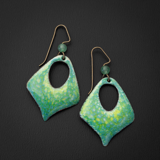 Handcrafted green enamel earrings with hints of yellow and blue in a diamond-shaped cutout design, paired with niobium ear wires and green stone bead accents, inspired by fresh spring meadows.
