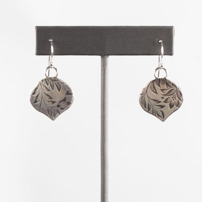 Handcrafted sterling silver earrings with etched botanical leaf and flower pattern, soft matte finish and organic shape – artisan nature-inspired jewelry by Divella Designs, shown on white background.