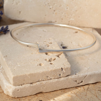 Silver bangle on a textured stone surface with lavender flowers