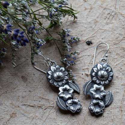 Handmade silver floral dangle earrings featuring layered botanical flower and leaf designs, artisan-crafted with oxidized sterling silver for a vintage nature-inspired look