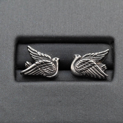 Pair of silver bird-shaped earrings on a gray background