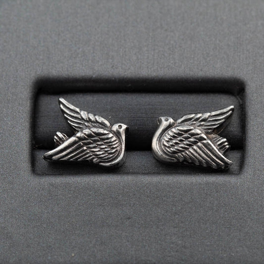 Pair of silver bird-shaped earrings on a gray background