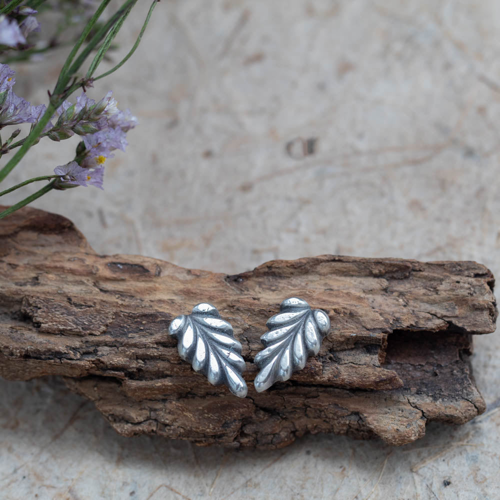 Sterling silver leaf stud earrings by Divella Designs, handmade in Vermont with satin finish, styled on bark with lichen and wildflowers