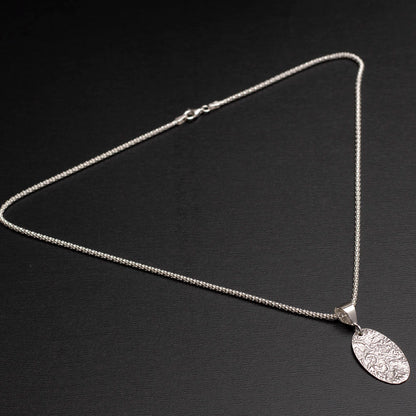 Sterling silver oval pendant necklace with textured landscape design on 18-inch chain.