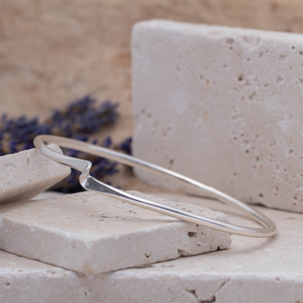 Handmade sterling silver twisted bangle with a subtle curve and polished fin