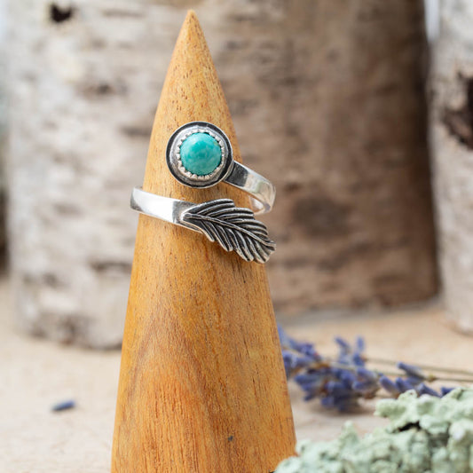 Silver ring with turquoise stone on a wooden cone with a natural background