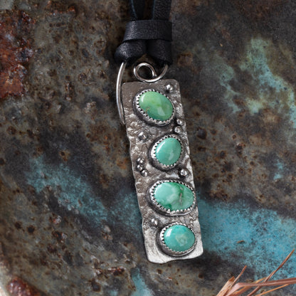 Necklace with a pendant featuring turquoise stones on a textured surface