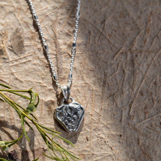 Handmade fine silver strawberry pendant necklace with botanical leaf details, featuring a whimsical nature-inspired design on a delicate silver chain.