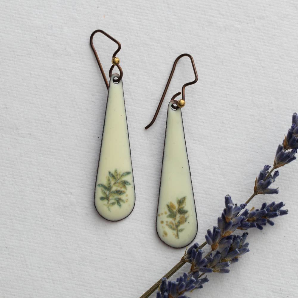 Teardrop-shaped earrings with floral design on a light background with lavender.