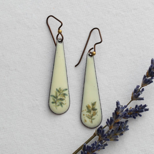 Teardrop-shaped earrings with floral design on a light background with lavender.