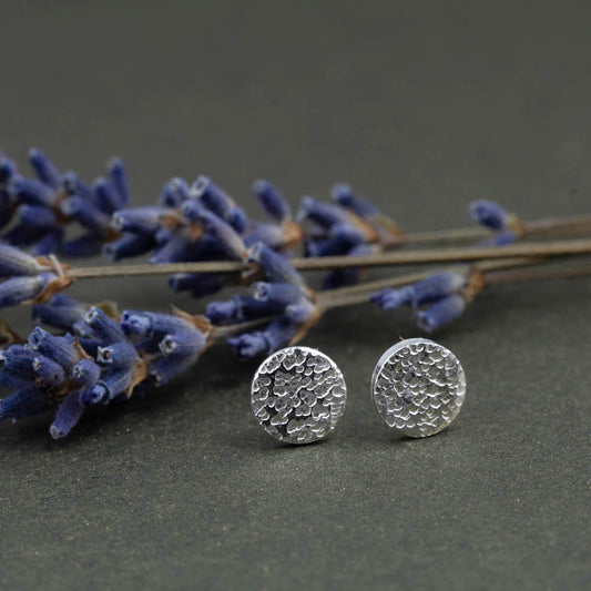 Minimalist textured silver circle studs on dark background
