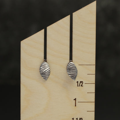 Handcrafted sterling silver leaf-shaped stud earrings with textured woodgrain pattern, minimalist nature-inspired jewelry for everyday wear.