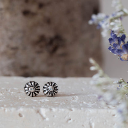 Tiny handmade sterling silver stud earrings with oxidized floral sunburst design, featuring 5mm round shape and minimalist vintage-inspired style.