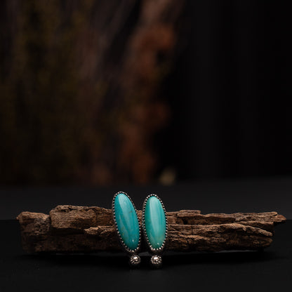 Handmade turquoise and sterling silver stud earrings with elongated oval stones and stamped silver accents. Southwestern-inspired artisan earrings with natural turquoise.