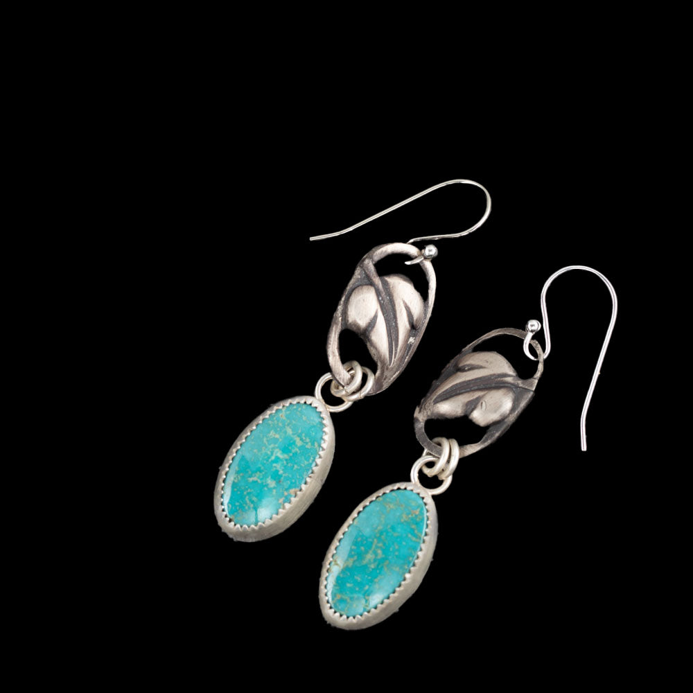 Turquoise sterling silver drop earrings with oval blue-green stones, fine silver settings, leaf accents, and sterling silver ear wires, handmade in Vermont by Divella Designs.