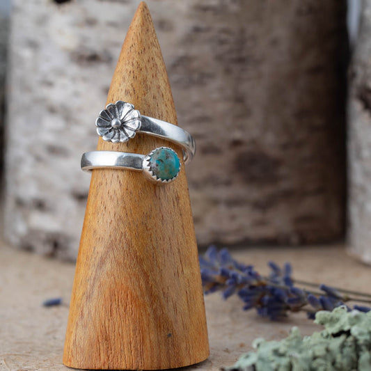Handmade sterling silver wrap ring with turquoise stone and flower detail on wooden ring cone