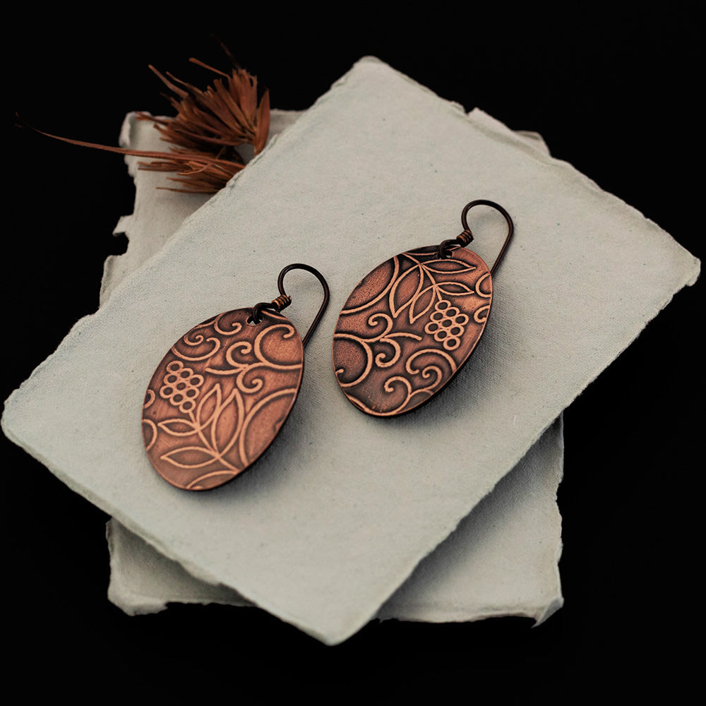 Embossed oval copper earrings with floral and vine pattern on niobium ear wires