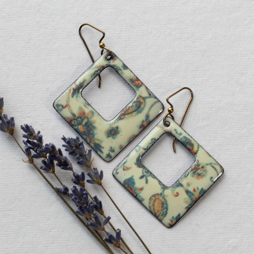 Pair of square-shaped earrings with floral pattern on a light background
