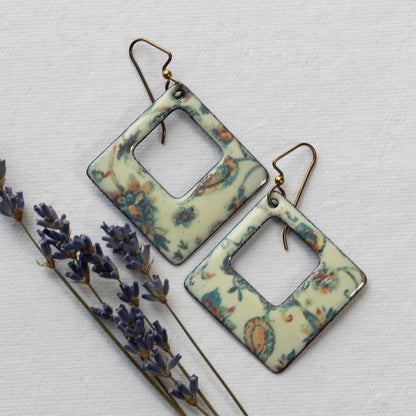 Pair of square-shaped earrings with floral pattern on a light background
