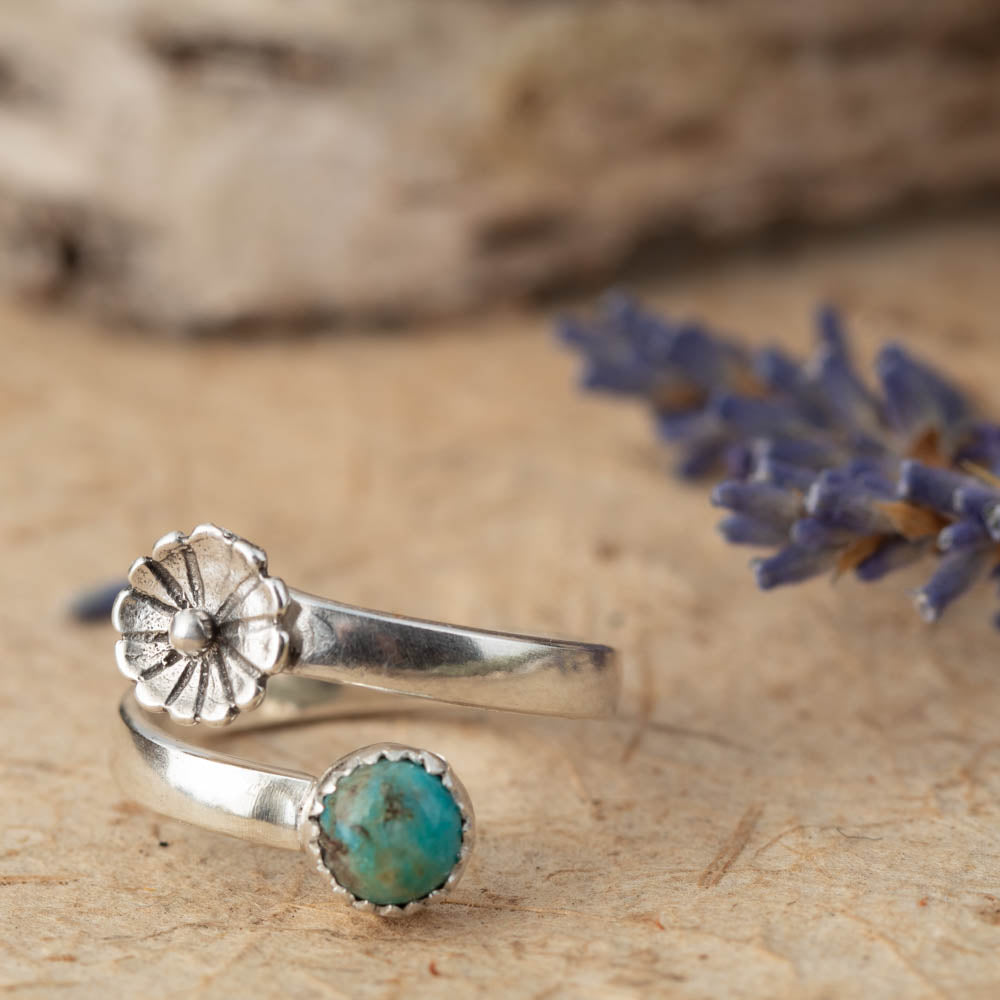 Silver ring with turquoise stone on a wooden surface with lavender.