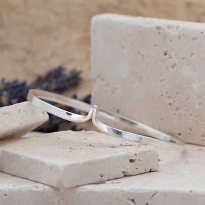 Silver bracelet on a stone surface with lavender in the background