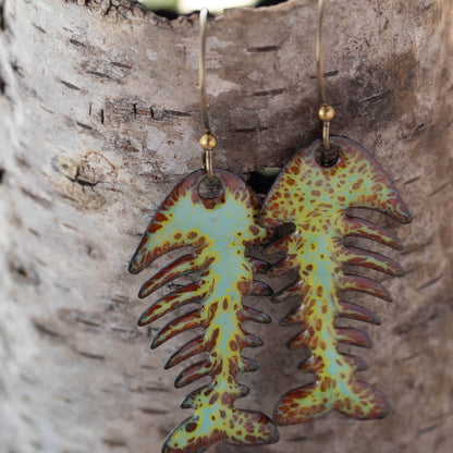 Fossil-style earrings with a colorful design on a wooden surface