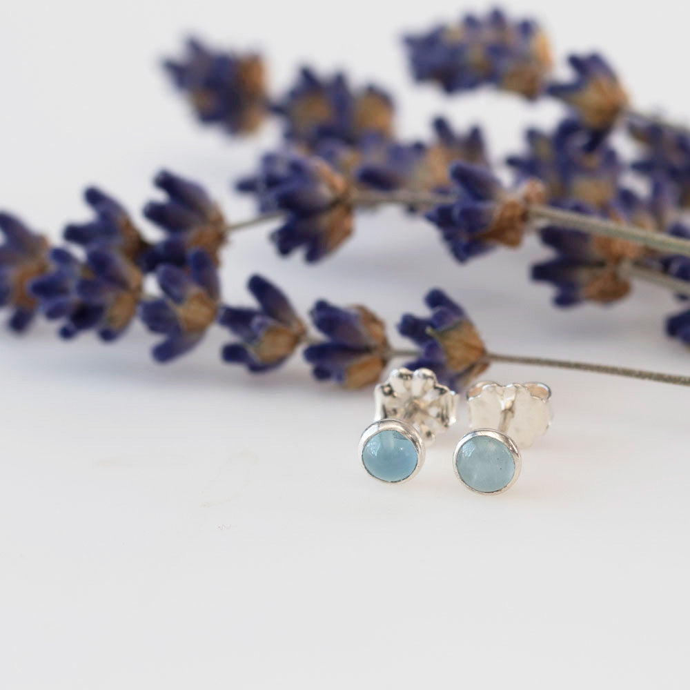 Aquamarine stud earrings set in sterling silver, displayed on a white background with lilac accents.