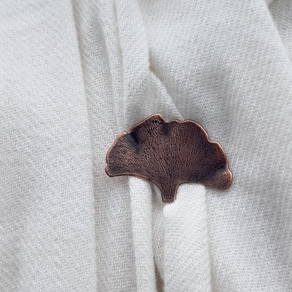 Handcrafted copper ginkgo leaf brooch with textured detail and organic fan shape, featuring nature-inspired botanical design and warm earthy patina. Close up view.