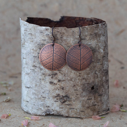 Handmade copper leaf print earrings with etched vein detail, featuring round disc shape and rustic botanical design inspired by nature