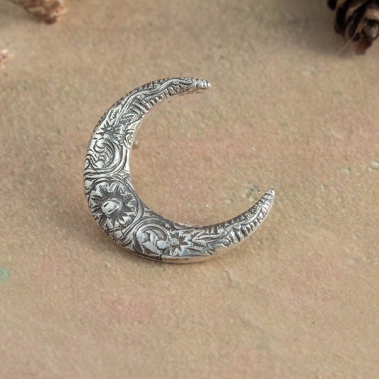 Decorative silver crescent moon on a textured beige surface