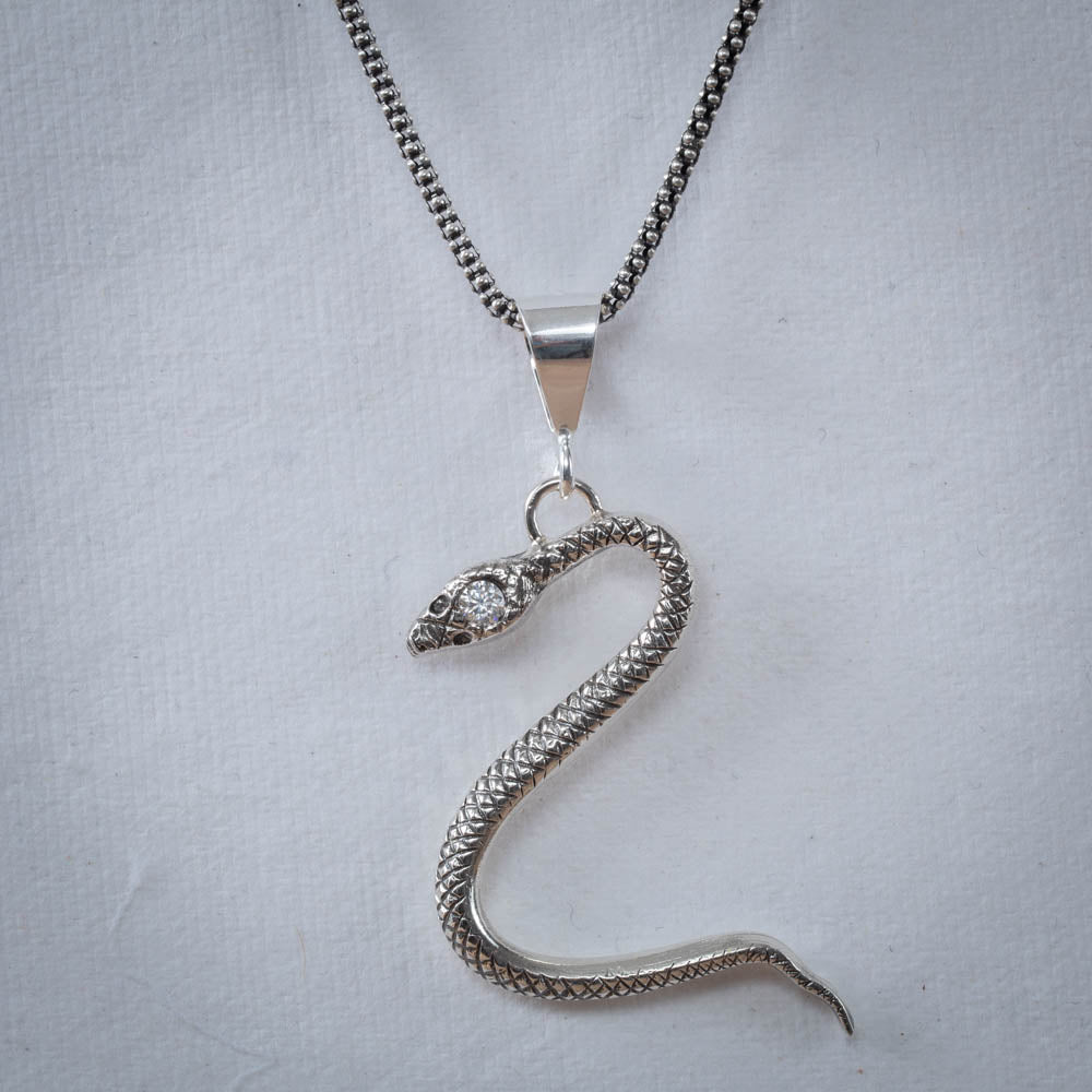 Silver snake pendant necklace on a light gray background