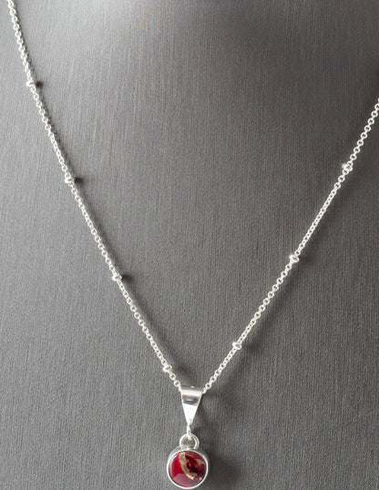 Dainty handmade sterling silver pendant necklace with round red and pink dahlia jasper stone, set on a fine chain with minimalist floral design and artisan elegance.