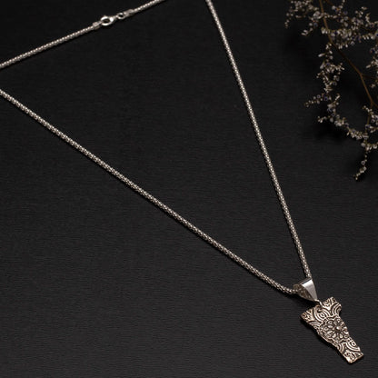 Textured fine silver vermont necklace with silver chain pictured on a black background with dried flowers.