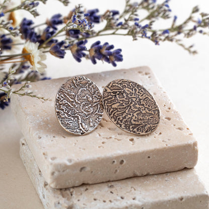 Handmade fine silver oval stud earrings with embossed organic texture, featuring earthy artisan style and oxidized finish for a nature-inspired look