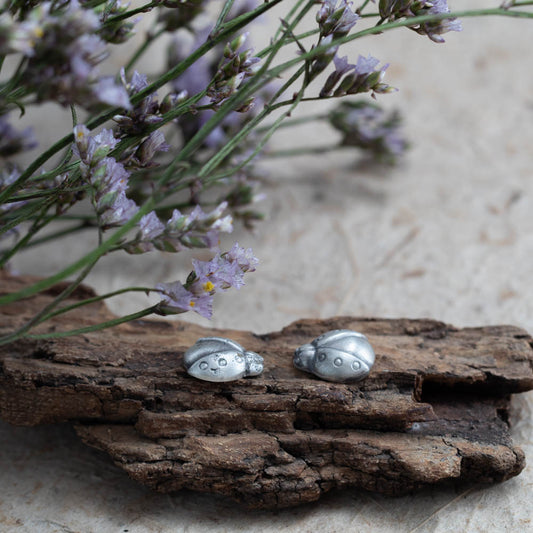 Sterling silver ladybug earrings by Divella Designs, handmade in Vermont with satin finish, styled on bark with lichen and wildflowers