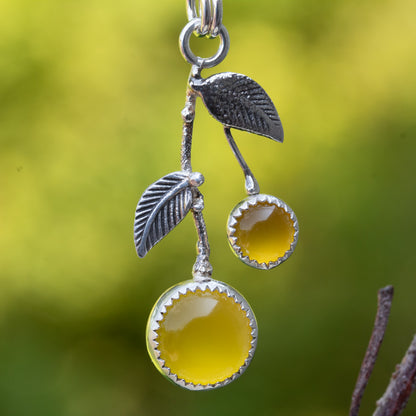 Sterling silver lemon drop necklace with yellow chalcedony stones and textured silver leaves against a soft green background.
